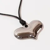 Collar con dije de corazón plateado y cordón negro.