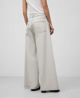 Pantalón palazzo de denim crudo para mujer, de tiro alto, con cierre de botón metálico, trabillas, bolsillos laterales y traseros, costura lateral desplazada al delantero de la pierna, pespuntes decorativos a contraste y parche logotipado en la espalda.