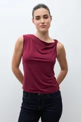 Top sin mangas color bordó, con escote asimétrico drapeado y ajuste al cuerpo.