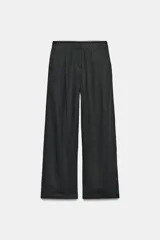 Pantalón de lino negro de tiro medio, con pernera recta, pinzas delanteras y detalle de puntilla en la cintura. Cuenta con bolsillos frontales y cierre con cremallera y botón.