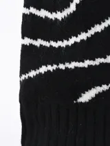 Gorro de lana tejido, color blanco, con diseño de rayas onduladas en hilo dorado y pompón de pelo sintético blanco en la parte superior.