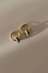 Par de aros tipo argolla dorados de acero quirúrgico, con una piedra natural de color gris translúcido colgando de cada uno.