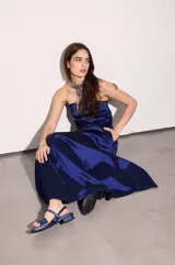 Vestido largo azul con escote strapless, corte suelto y fluido, confeccionado en tafeta con efecto tornasolado, y bolsillos ocultos en los laterales.