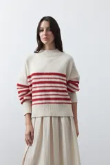 Polera de tejido de punto con diseño a rayas horizontales en color azul marino sobre base beige. Presenta cuello alto, mangas largas con puños acanalados y una silueta relajada.