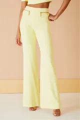 Pantalón amarillo de tiro alto y corte acampanado, con bolsillos frontales con cierre dorado.
