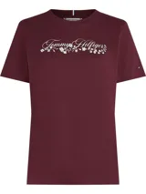 Remera de algodón Tommy Hilfiger en color bordó, con cuello redondo y mangas cortas. Presenta un diseño gráfico en el pecho que combina el logo de la marca con detalles florales bordados en color blanco. Incluye la pequeña bandera distintiva de la marca bordada en la manga.