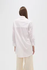 Camisa marrón holgada de algodón con cuello clásico, cierre frontal con botones y mangas largas con puños abotonados.