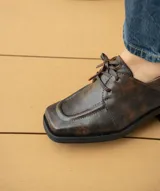 Zapato acordonado de cuero vacuno con acabado desgastado, de horma cuadrada y suela de goma con pequeño taco.