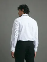 Camisa de vestir blanca de corte clásico, con cuello rígido y mangas largas con puños abotonados.