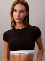 Bralette tipo t-shirt de Calvin Klein, confeccionado en mezcla de algodón y modal. Presenta diseño de cuello redondo, mangas cortas y banda elástica inferior con el logo de la marca estampado.