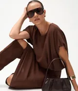 Blusa corta de estilo balonê confeccionada en tejido de viscosa, con mangas cortas amplias, escote redondo y ruedo fruncido que genera un efecto voluminoso.