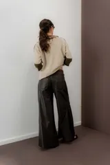 Pantalón de cuero ovino italiano de tiro medio y corte ancho. Presenta costuras diagonales en las piernas que aportan volumen y vuelo, con pretina y pasacintos confeccionados en gamuza al tono.