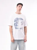 Remera blanca de algodón con estampado abstracto en tonos grises y azules.