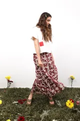 Falda larga de gasa con estampado tipográfico en tonos bordó sobre fondo beige. Presenta un diseño de doble tela con caída fluida y cierre lateral oculto.