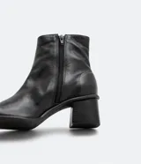 Bota de cuero de caña media para mujer, con punta cuadrada y tacón bloque de 6 cm. Presenta un cierre de cremallera en el lateral interno y una costura central decorativa en la parte frontal.