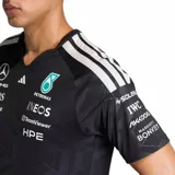 Camiseta técnica de manga corta Adidas del equipo Mercedes-AMG Petronas F1, color negro con estampado geométrico sutil y múltiples logotipos de patrocinadores en el frente y mangas. Presenta cuello en V con detalle en color turquesa y las icónicas tres tiras de Adidas en los hombros.