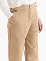 Pantalón de gabardina color camel, de corte relajado y tiro alto, con recortes delanteros, pinzas en la entrepierna y bolsillos traseros tipo jeaneros.
