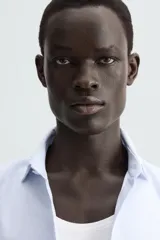 Camisa de algodón de manga larga, color celeste claro, con cuello italiano y cierre frontal de botonadura.