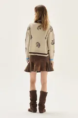 Sweater de punto color bordó con diseño de flores estampadas en tono crema, cuello redondo y puños con detalle de franjas en contraste. Presenta un bordado pequeño en el pecho.