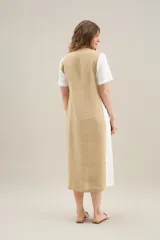 Vestido largo de lino de silueta relajada, con escote redondo, mangas cortas y bolsillos laterales. Cuenta con un diseño bicolor que combina un panel central en color tostado y los laterales y mangas en color blanco.