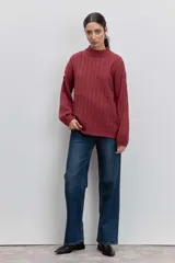 Sweater de tejido de punto color bordó, con cuello alto, mangas largas con puños ajustados y diseño de trenzas verticales.