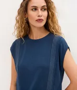 Blusa de viscosa color azul, con corte recto, cuello redondo y mangas cortas sin sisa. Presenta detalles de pespuntes verticales en color blanco en el frente.