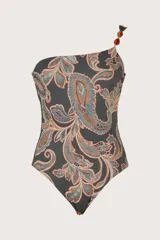 Traje de baño entero asimétrico con diseño de un solo hombro, decorado con cuentas de resina en el tirante. Presenta un estampado tipo paisley en tonos oscuros, ocres y azulados.