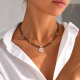 Collar de cristalitos facetados oscuros con cuentas y dije de plata 925 en forma de círculo con cruz calada.