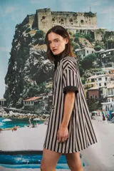 Vestido camisero corto, con cuello mao, botones a tono y parche con logo en el frente. Diseño a rayas verticales negras y blancas.