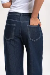 Pantalón de jean azul oscuro de corte recto y tiro medio-alto, con costuras a la vista en color blanco que resaltan el diseño.