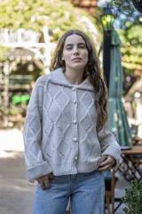 Saco tejido de punto con diseño de ochos y trenzas, color negro. Presenta cuello estilo camisero, cierre frontal con botones tipo joya, mangas holgadas y silueta oversize.