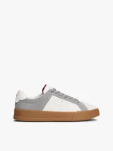 Zapatillas de tenis Tommy Hilfiger de corte bajo, confeccionadas en piel nobuk con paneles de texturas mixtas en blanco y gris. Presentan suela de goma color caramelo, cierre con cordones y detalles distintivos de la marca en la lengüeta, lateral y talón.