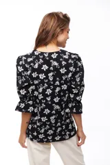 Blusa negra con estampado floral blanco, escote en V y mangas 3/4 con volados.