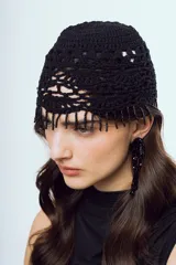 Gorro negro tejido a crochet de diseño artesanal con trama calada y flecos de mostacillas colgantes en el borde frontal.