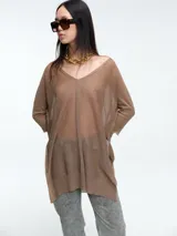 Sweater tipo túnica de tejido liviano con hilo brillante y transparencia sutil. Presenta escote en V, mangas largas relajadas y un corte amplio con largo generoso.