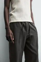 Pantalón de corte regular fit confeccionado en mezcla de algodón y lino. Presenta cintura elástica con cordón ajustable, cierre frontal con cremallera y botón, bolsillos laterales y bolsillo trasero de vivo con botón.