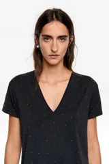 Camiseta negra de corte recto con escote en pico y manga corta. Presenta una sutil aplicación de pequeñas piedras brillantes distribuidas por toda la prenda.