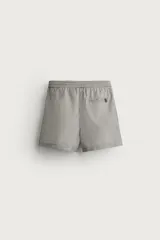 Short de baño confeccionado en tejido técnico con patrón de rayas verticales en tonos azul marino y blanco, con cintura elástica ajustable mediante cordón y bolsillos laterales.