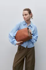 Camisa de viscosa color celeste, de calce amplio y caída fluida, con cuello clásico, cierre frontal de botones y detalles calados en mangas y delantero.