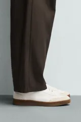 Zapatillas deportivas de hombre, de estilo retro, color blanco con puntera de gamuza color crema, detalle trasero en cuero negro y suela marrón.