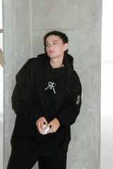 Buzo negro oversize de frisa con capucha amplia, bolsillo canguro, terminaciones de puño y ruedo con rib, y logo bordado en el centro delantero.