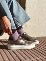 Zapatillas deportivas de cuero color peltre, con cordones negros y suela de goma blanca.