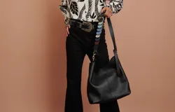Cartera tipo shopper de cuero sintético negro, con diseño estructurado y costuras pespunteadas visibles al frente. Cuenta con doble asa de hombro fija y correa desmontable.