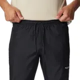 Pantalón deportivo de hombre, color negro, diseñado para actividades al aire libre. Presenta cintura elástica con ajuste, bolsillos laterales con cierre y puños elásticos en los tobillos. Confeccionado con tecnología repelente al agua y resistente a las manchas.