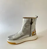 Botas cortas de cuero plateado, con diseño híbrido que combina la estética texana con una suela chunky blanca y detalle de arte lateral creado por Carolina De Cunto.