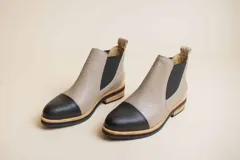 Botas Chelsea de cuero color visón con puntera negra, elástico lateral negro y suela de madera.