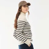 Sweater de punto con cuello alto, diseño de rayas horizontales negras sobre base beige, manga larga y ajuste al cuerpo.