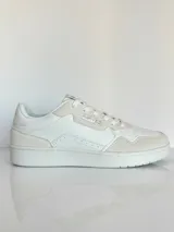 Championes urbanos Rusty modelo Meier, color blanco con detalles en tono crema. Presentan una combinación de cuero sintético liso y paneles de gamuza, con perforaciones decorativas en los laterales y la puntera, y suela de goma al tono.