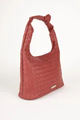 Cartera marrón de símil cuero trenzado con asa fija anudada. Cuenta con tres bolsillos interiores.