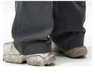 Pantalón cargo ancho de algodón gabardina color beige claro, con cintura elástica y regulable, y múltiples bolsillos cargo con pliegues en las piernas.